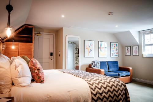 泰晤士河畔金斯顿昆世海德酒店的一间卧室配有一张大床和一张蓝色椅子