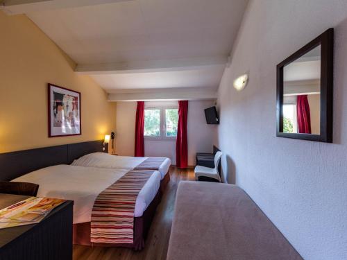 艾格-莫尔特Noemys Aigues-Mortes - Hotel avec piscine的酒店客房设有床和窗户。