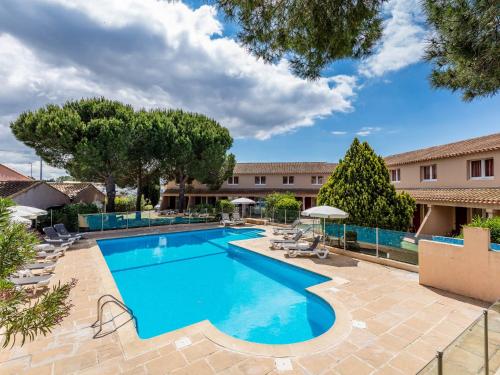 艾格-莫尔特Noemys Aigues-Mortes - Hotel avec piscine的度假村的游泳池配有椅子和遮阳伞