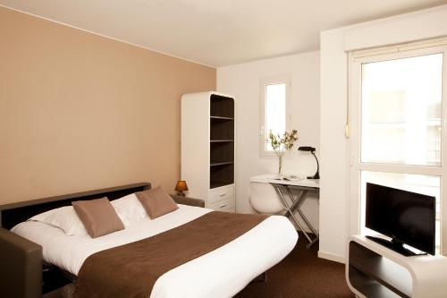拉罗谢尔罗谢尔米尼姆公园和套房酒店的一间卧室配有一张床、一张书桌和一台电视