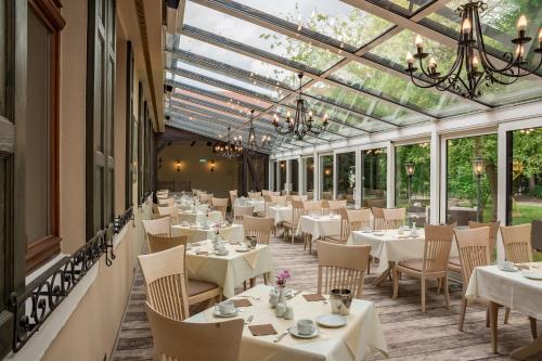 唐格明德坦格尔明德施沃泽阿德勒酒店的餐厅设有白色的桌椅和窗户。