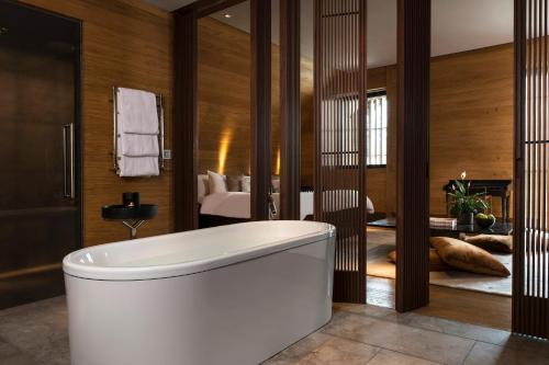安德马特切蒂安德马特酒店的一间带白色浴缸的浴室和一间卧室