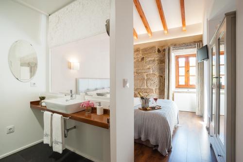 蒙达里斯A Cantaruxa Maruxa Turismo Rural的一间带水槽的浴室和一张位于客房内的床