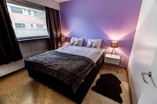 索丹屈莱Kuukkeli Apartments Sodankylä的紫色卧室设有一张床和一个窗户