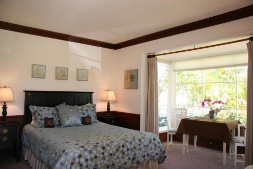 奥海Ojai Retreat & Inn的一间卧室配有一张床、一张书桌和一个窗户。