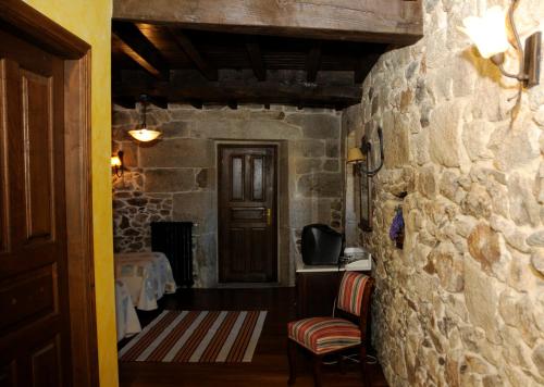 Casarellos卡萨瑞洛斯酒店的一间设有石墙、两把椅子和一扇门的房间