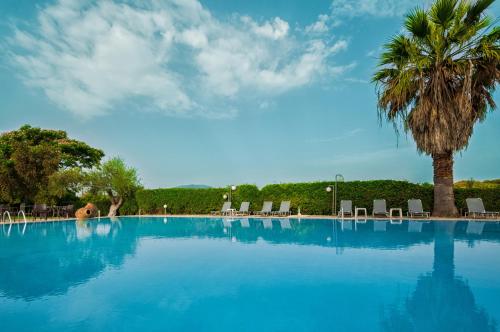 Agios AvgoustinosHotel Sias Resort的一个带棕榈树和椅子的大型游泳池