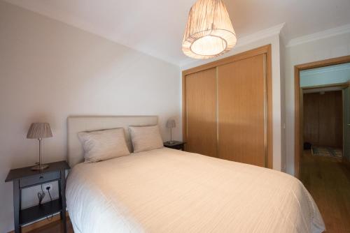 马托西纽什波尔图河海码头公寓的卧室配有白色的床和吊灯。