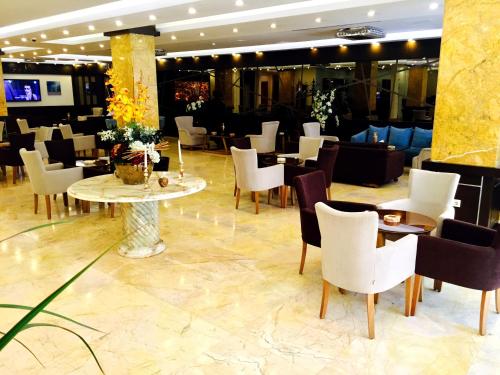 埃尔比勒埃尔比勒嘉逸豪庭酒店的大堂内的餐厅,配有白色的椅子和桌子