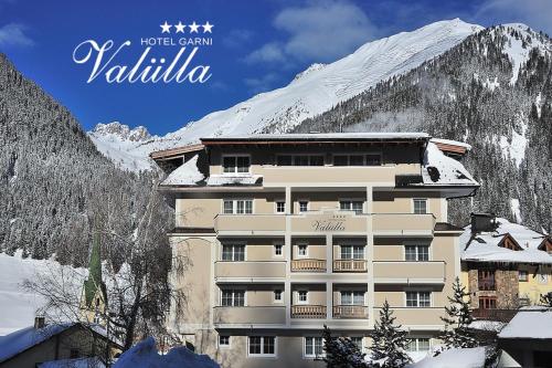 伊施格尔Hotel Garni Valülla的雪覆盖的山前的建筑物