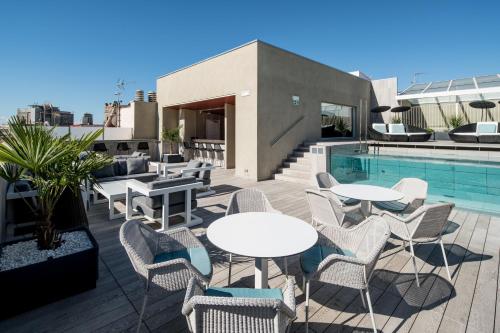 巴塞罗那加泰罗尼亚马达林思酒店的游泳池旁带桌椅的天井
