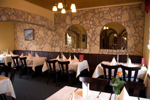 伦茨堡伦茨堡酒店的一间带桌椅和石墙的用餐室