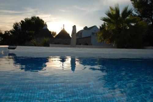 马丁纳弗兰卡Masseria Battaglini的一座游泳池位于一座享有日落美景的房屋前