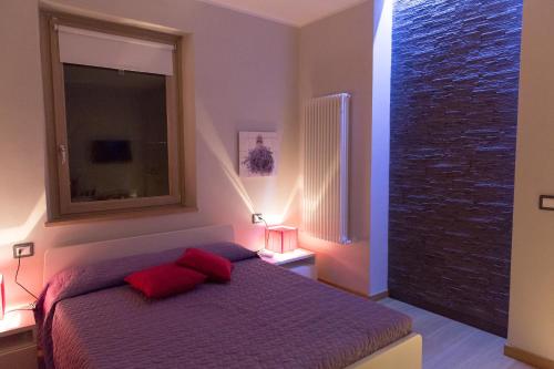 卡波迪蒙泰La Suite Sul Lago的一间卧室配有一张带红色枕头的床和一扇窗户