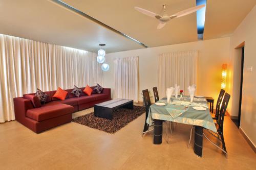 ShoranūrThe River Retreat Heritage Ayurvedic Resort的客厅配有红色的沙发和桌子