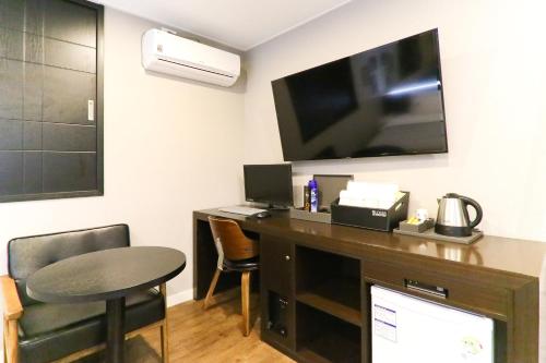 釜山路易斯酒店的客房设有书桌、电视和桌子