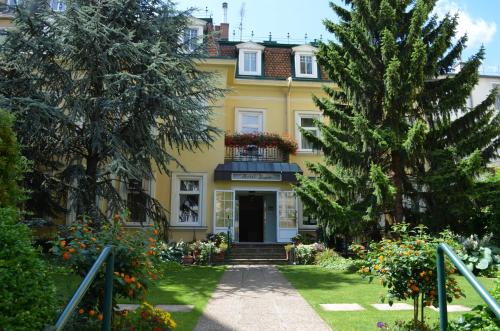 维也纳Hotel Jäger - family tradition since 1911的花园中带阳台的黄色房子