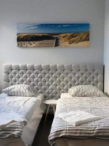 格丁尼亚Panorama Gdynia Rooms的一间卧室设有两张床,墙上挂着一幅画