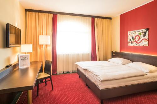 佩希托尔茨多夫卡尔维特酒店的配有一张床、一张书桌和一扇窗户的酒店客房