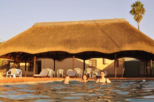 奥马鲁鲁卡沙纳纳米比亚旅馆的一群人在茅草屋顶的游泳池游泳