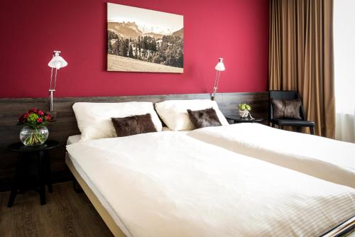 Menzingen奥赫森酒店的卧室配有一张白色大床和红色墙壁