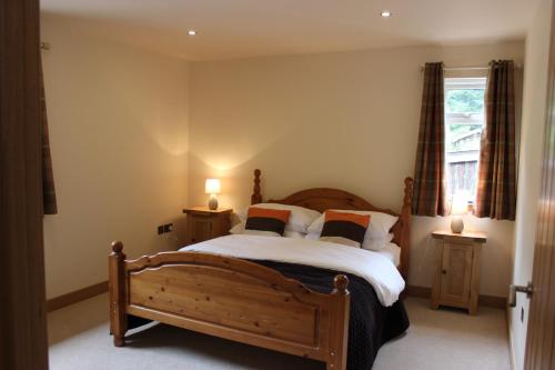 因弗莫里斯顿Loch Ness Highland Cottages with partial Loch View的一间卧室配有木床和2个床头柜