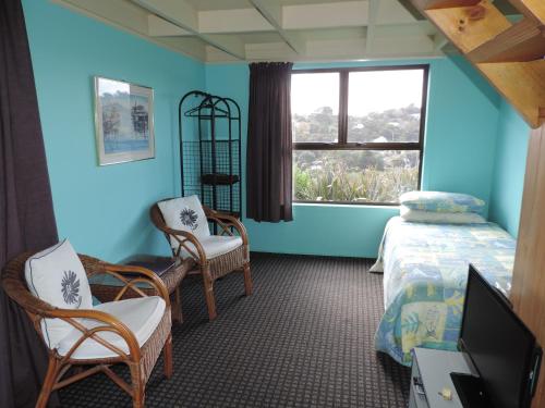 欧尼罗亚怀赫科岛塔瓦山林小屋 - 仅限成人的一间卧室配有一张床、两把椅子和一个窗户