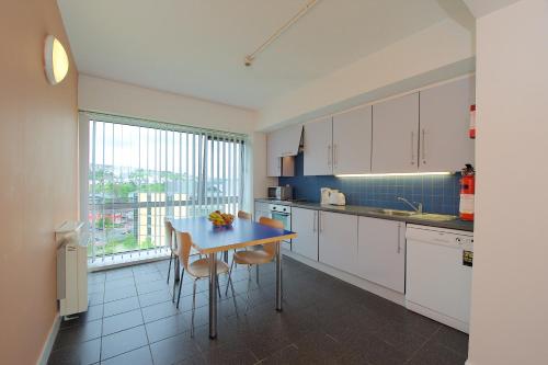 科克Victoria Mills Apartments - UCC Summer Beds的厨房配有白色橱柜和桌椅