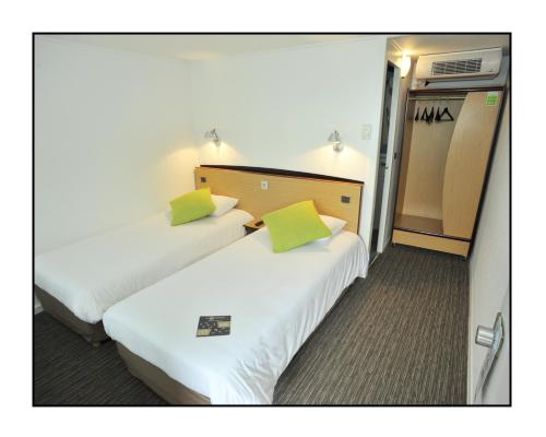 勒河畔的圣马丁Kyriad Châlons-En-Champagne - Saint-Martin的配有绿色枕头的酒店客房内的两张床