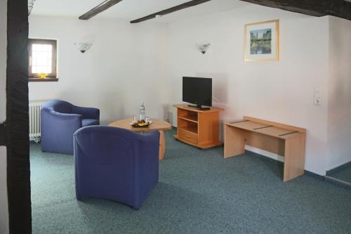 瓦尔多夫多尔尼尔歇斯豪斯酒店的客厅配有两把椅子、一台电视和一张桌子