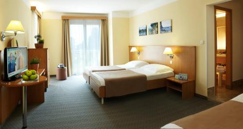 波尔托罗Hotel Neptun - Terme & Wellness Lifeclass的酒店客房,配有床和电视