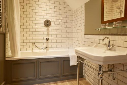 巴克法斯特利Dartbridge Inn by Greene King Inns的浴室配有2个盥洗盆和1个浴缸。