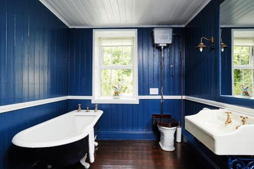 CastlehavenThe Castle的蓝色的浴室设有两个盥洗盆和一个浴缸。