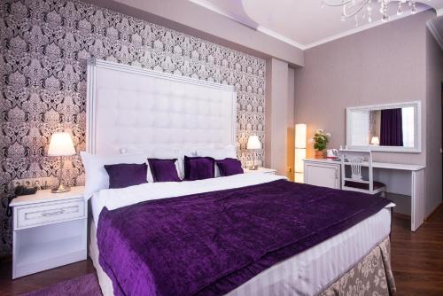 克拉斯诺达尔Hotel De Paris的紫色卧室配有一张带紫色枕头的大床