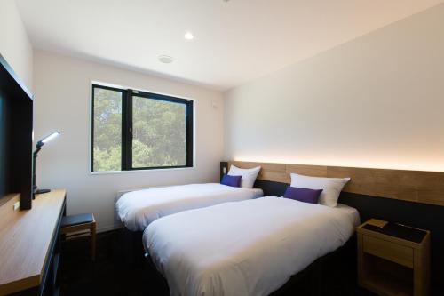 二世古奥尔韦斯雪谷旅馆的带窗户的客房内的两张床