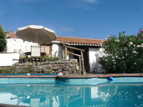 格拉纳迪利亚德亚沃纳佩帕乡村民宿的一个带遮阳伞和房子的游泳池