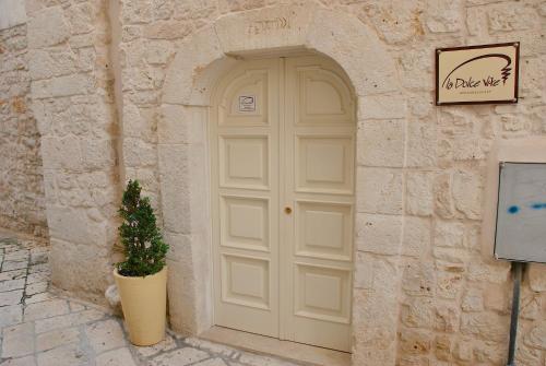 图里La Dolce Vite的石屋中一扇白色门,有盆栽