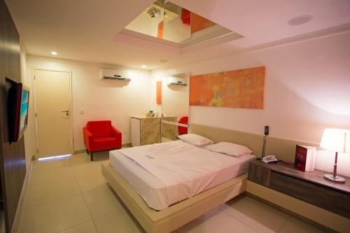 萨尔瓦多DOM Suites motel (Adult Only)的一间卧室配有一张床和一张红色椅子