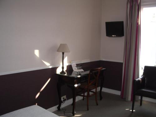 尼斯圣休伯特酒店的客房配有带台灯和椅子的书桌