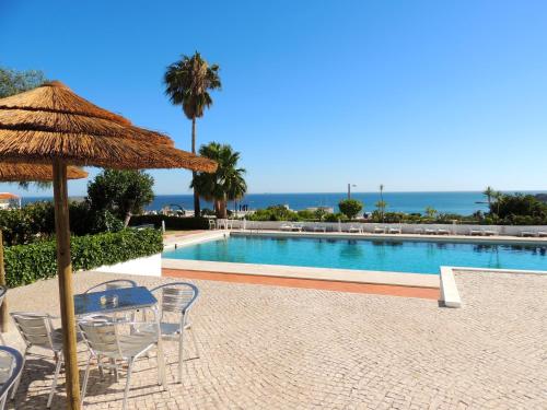 阿尔布费拉奥尔马尔公寓酒店的一个带桌椅和草伞的游泳池