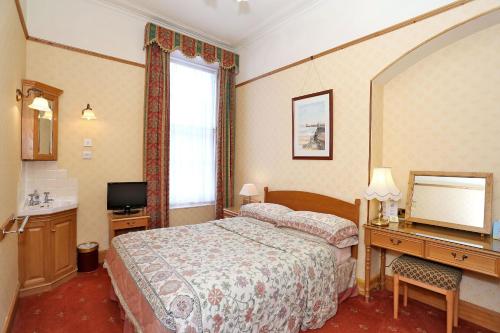 阿伯丁Butlers Guest House的酒店客房配有一张床、一张书桌和一台电视。