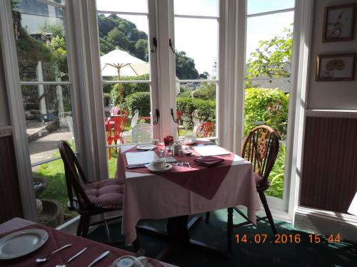 林茅斯Orchard House Hotel的一间带桌椅和窗户的用餐室