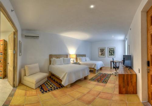 普埃布拉卡萨雷纳精品酒店的一间卧室配有两张床、一把椅子和电视