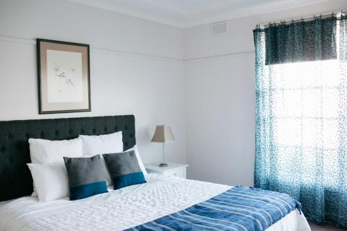 凯恩顿戈尔迪派波尼顿乡村民宿的一间卧室配有一张带蓝色窗帘的床和一扇窗户