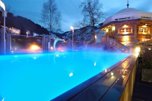萨尔巴赫Stammhaus im Hotel Alpine Palace的大楼前的蓝色灯光游泳池