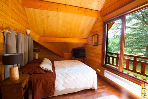 Condat-sur-Vienne小木屋住宿加早餐旅馆的小木屋内的卧室,配有床和窗户