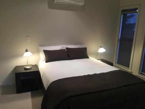 金斯科特金斯科特湾公寓式酒店的一间卧室配有一张带两盏灯的大型白色床。