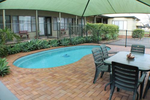 福布斯福布斯湖汽车旅馆的一个带桌椅和遮阳伞的游泳池