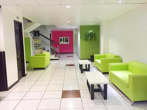 图斯特拉古铁雷斯Hotel Plazha的一间设有绿色和粉红色椅子和桌子的等候室