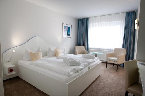 维滕Frühstückshotel Seemannsbraut Amrum - adults only的白色的卧室配有一张白色的大床和一张桌子